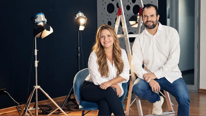 Diana Cardona y Andrés Figueroa sentados en su estudio, rodeados de luces de grabación.